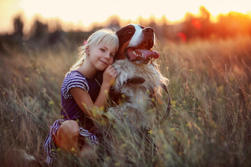 girl hugs her dog at sunset