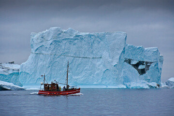 Converted fishing boat among enormous icebergs in Disko Bay, Illulissat, Greenland © Michele Burgess
