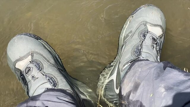 A slow motion view of a fly Fishermans wading boats hanging in the river.