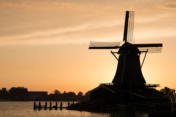 Fototapeta na wymiar Dutch windmill silhouette next to a lake at sunset
