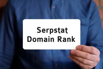 Domain rank text on a white sign in the hand of a man in a blue shirt