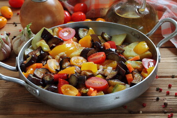 Vegetable stew with eggplant and zucchini on a wooden background
