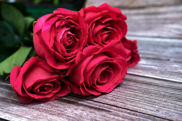 Naklejka premium A bouquet of five red roses on a wooden background