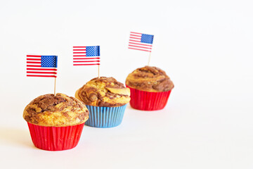 Homemade marble chocolate muffins in a row with decoration for Independence Day. American flag decorates cakes. Light background, daylight. 4th of July party dessert. Free space for your text