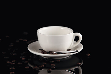 Empty white cup and coffee beans on a dark background with reflection