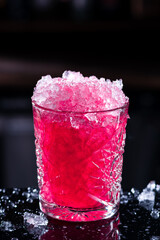 purple-pink cocktail with crash ice in a bar