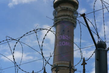 Ostankino tv tower through Barbed wire.  High technology in everyday. Telephoto lens. Transl. of  inscription - Stay home. Coronavirus pandemic.