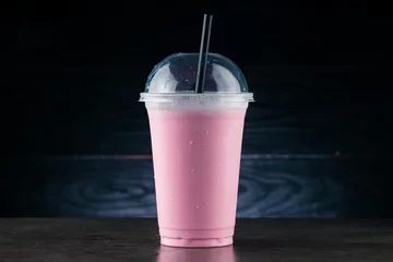 Fotobehang cherry milkshake in plastic glass on a dark background. cherry milkshake in takeaway cup © smspsy