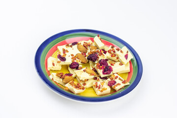 White chocolate with dried berries, fruits and almonds on the striped saucer.