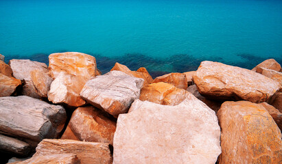 Background with huge sharp stones against a turquoise sea in Mahdia. Tunisia