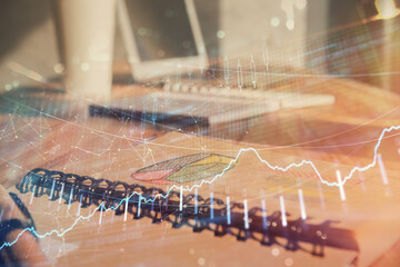 Double exposure of financial chart drawings and desk with open notebook background. Concept of forex market