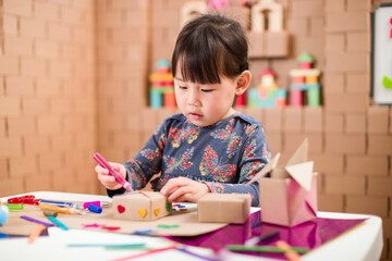 toddler girl  making craft by using cardboard for homeschooling