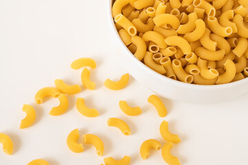 Raw dry uncooked Elbow Macaroni pasta spaghetti on white background. Good for basil tomato pesto sauce Homemade fresh Italian food organic whole wheat vegan spaghetti noodle for a healthy meal