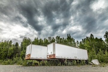 Parked semi-truck trailers on a dirt road in Alaska