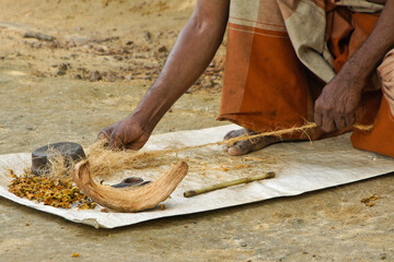 Man twisting coconut husk fiber (coir) into twine, Sri Lanka