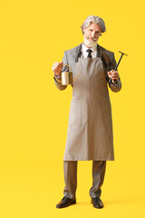 Senior businessman with gardening tools on color background