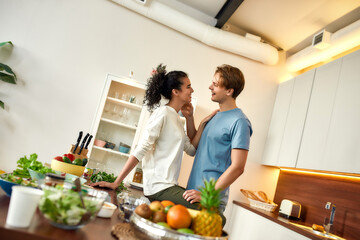 Happy couple, vegetarians looking into each other eyes before preparing a healthy meal in the kitchen together. Vegetarianism, healthy food, diet concept
