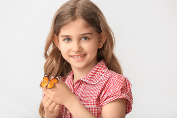 Cute little girl with butterfly on light background