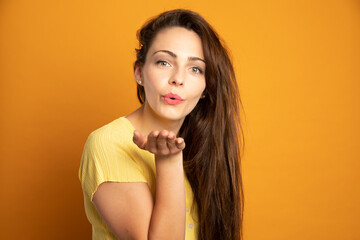 young woman sends a kiss on an orange background