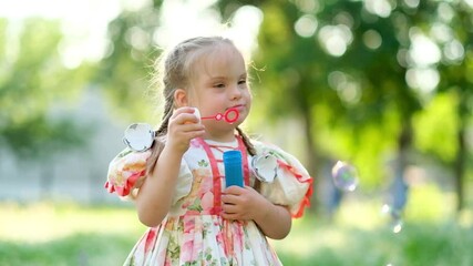 A girl with Down syndrome blows bubbles. The daily life of a child with disabilities. Chromosomal genetic disorder in a child.