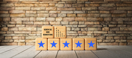 Fototapeta na wymiar cubes with stars and German message for GIVE YOUR RATING on wooden surface in front of a brick wall background