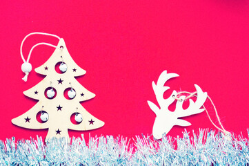 Christmas composition. Christmas wooden decorations and tinsel on a red background. Flat layout, top view, space for text.