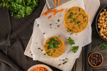 Raw veggie burger with chickpeas, vegetables and parsley leaves on kitchen countertop