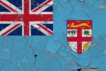 Fiji flag close up grungy, damaged and scratched on wall peeling off paint to see inside surface....