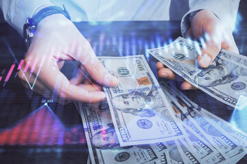 Multi exposure of financial graph drawing hologram and USA dollars bills and man hands. Analysis concept.