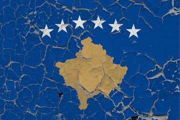 Kosovo flag close up grungy, damaged and scratched on wall peeling off paint to see inside surface. Vintage National Concept.