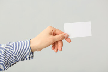 Female hand with blank business card on light background