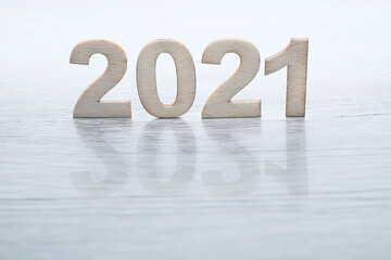 Block letters on 2021 cast shadow on wooden table 