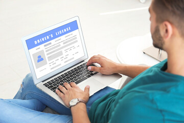 Man filling in driver's license form online on website using laptop