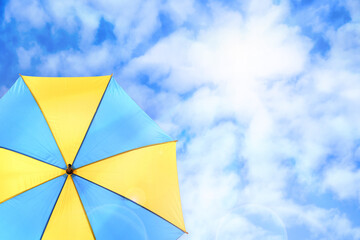 Modern bright umbrella against blue sky, space for text. Sun protection