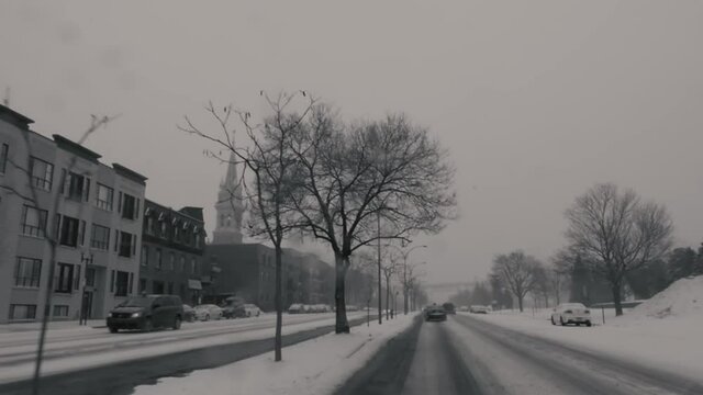 MONTREAL, CANADA - JANUARY 19 2019 Black and white dashboard camera shot of slow traffic on renee levesque street in winter. Cathedral tower in the background