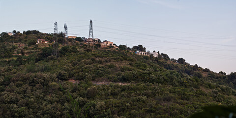 Fototapeta na wymiar Panoramic view of Hill Top with Trees High Voltage Towers and Wires of Domestic Power Line over Buildings near Nice City, France