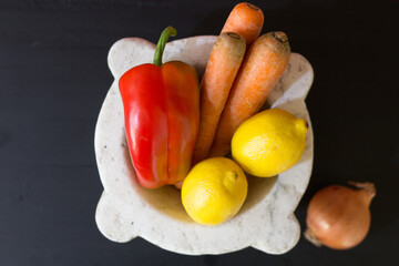 vegetables over marble bowl on wooden table