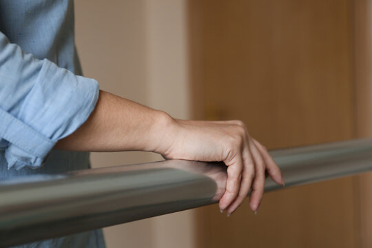 Woman leaning on metal railing indoors, closeup