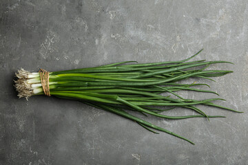 Fresh green spring onions on grey table, top view