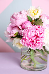Bouquet of beautiful peonies in vase on lilac table