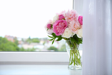 Beautiful peony bouquet in vase on windowsill indoors. Space for text