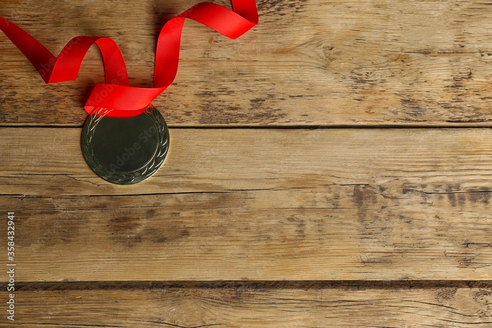 Wall mural medal with red ribbon on wooden background, top view. space for design