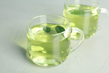 Cups of aromatic green tea on light table
