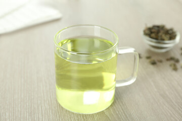 Cup of aromatic green tea on light wooden table