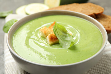Tasty homemade zucchini cream soup in bowl on table, closeup