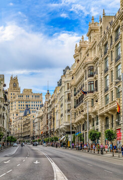 Beautiful buildings on the famous Gran Via shopping street and people walking in the center of the city in Madrid, Spain