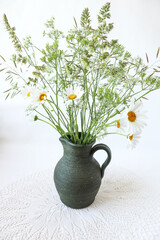  Bouquet of wild flowers in a ceramic vase close-up on a white background, vertical frame.