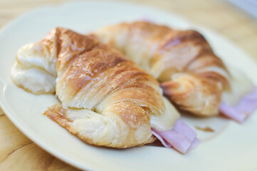 Fresh croissants with ham and cheese on plate