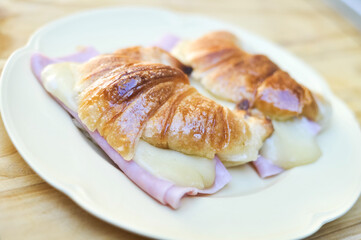 Fresh croissants with ham and cheese on plate
