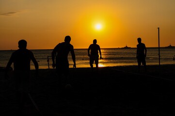 Fototapeta na wymiar Amateurs playing football at Jumeira beach in Santa Marta, Colombia during sunset.